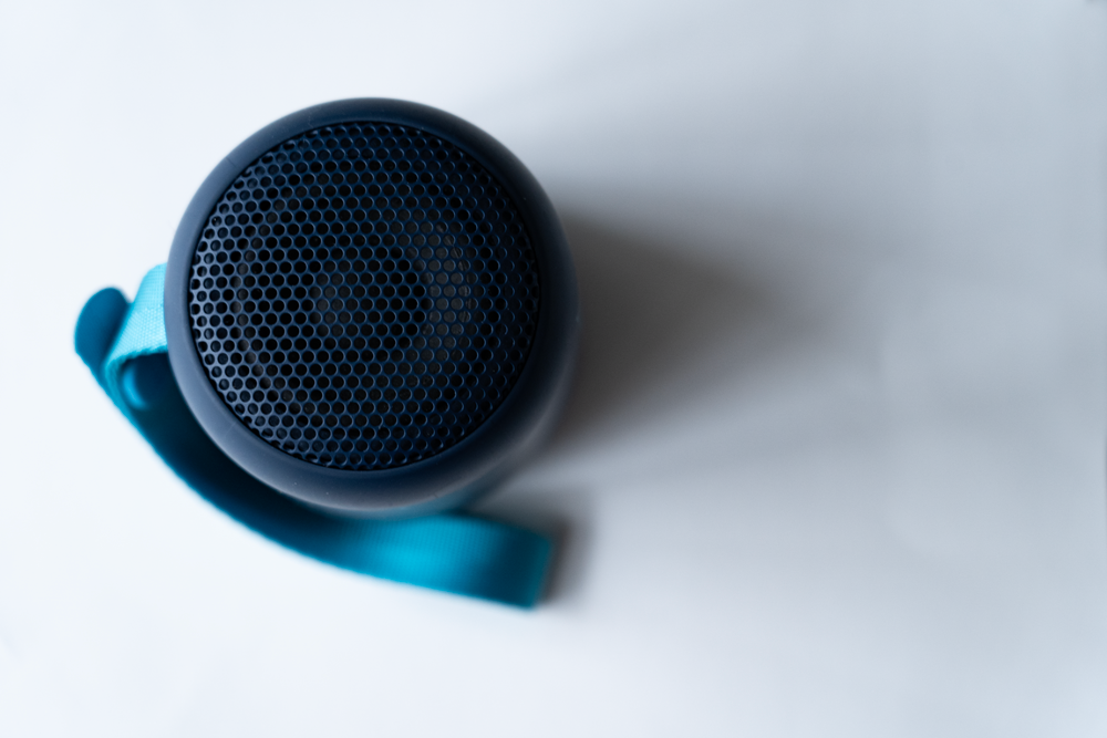 The picture is a photo showing a circle round blue soundbox from above.